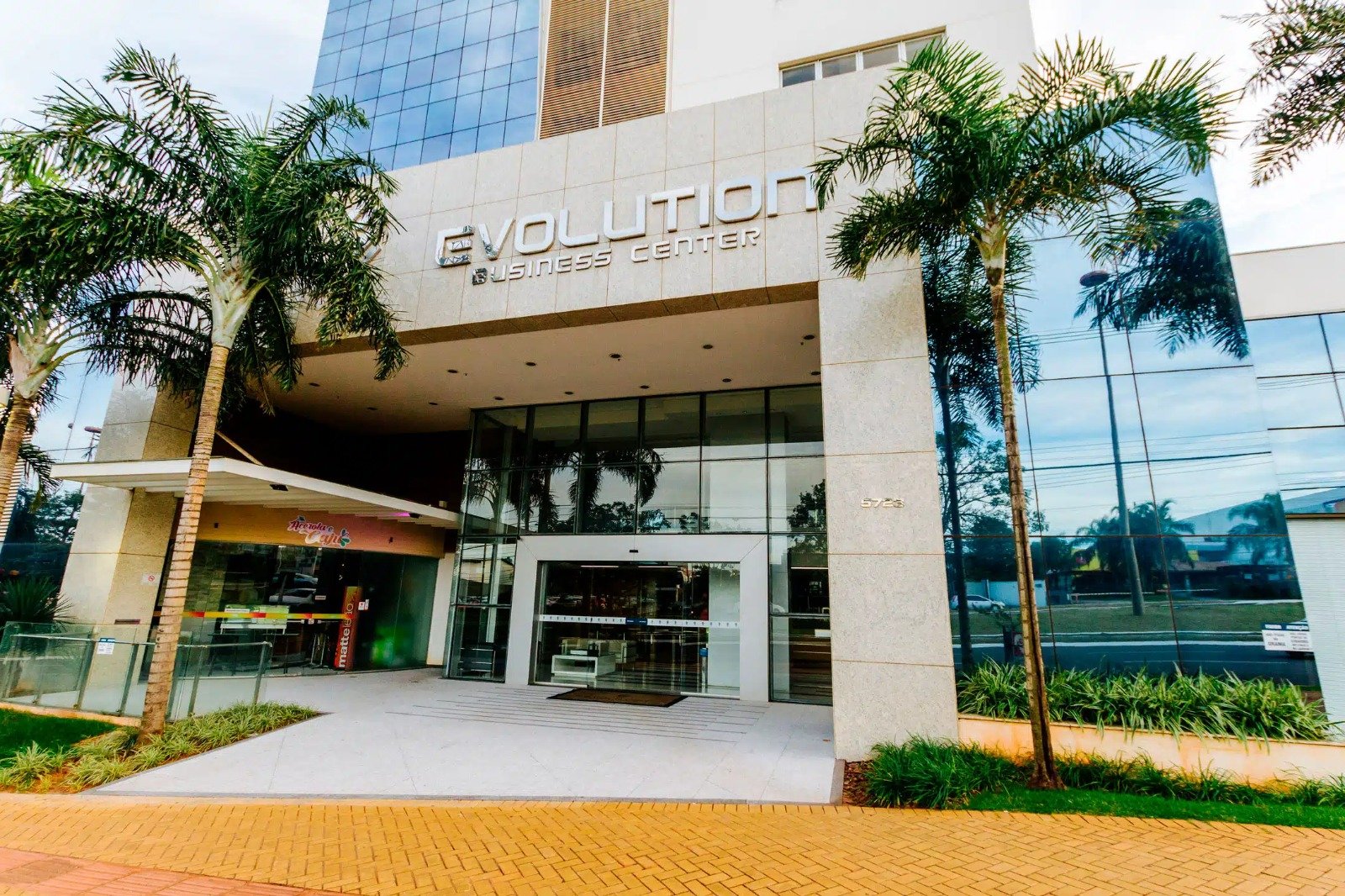 Fachada do Evolution Business Center, edifício onde fica o escritório da Spes Advocacia, com palmeiras e entrada em vidro